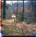 A cautionary sign in a colorful autumn forest warns of restricted access.
